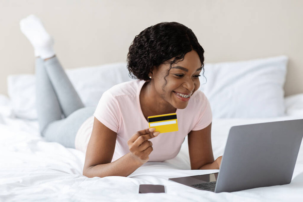 Женщина делает заказ с кредитной карты и ноутбука в постели - Фото, изображение