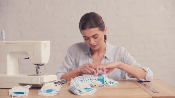 Seamstress counting medical masks near sewing machine  - Filmagem, Vídeo