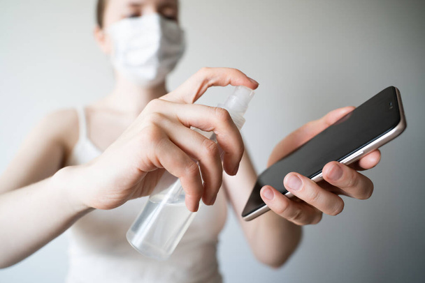 Cleaning mobile phone to eliminate germs, coronavirus Covid-19. Woman hands cleaning smartphone by alcohol hand sanitizer and wipe with cloth - Photo, image