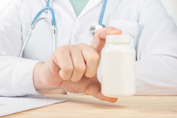 Doctor Showing A Bottle Of Pills To The Patient. specialist holding big jar of supplements, nutrition rich in vitamins. Doctor Holding An Unlabeled Bottle Of Tablets - Photo, Image
