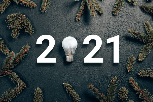 2021年アイデア最小限のコンセプト。暗いグラデーションの背景にガラス輝く電球とトウヒの枝を持つ白い数字。休日構成 - 写真・画像