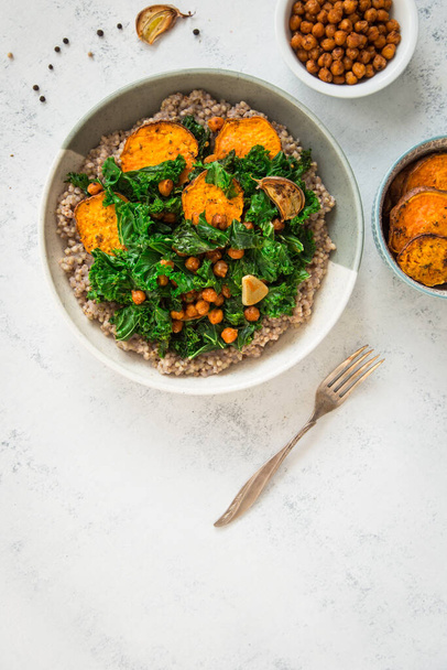Vegan dish with buckwheat, chickpeas, sweet potato, and kale in a bowl. Comfort food. - Foto, Bild