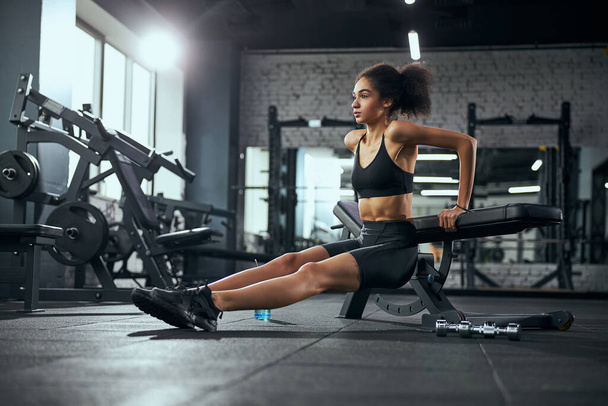 Geconcentreerde internationale vrouw doet workouts voor armen - Foto, afbeelding
