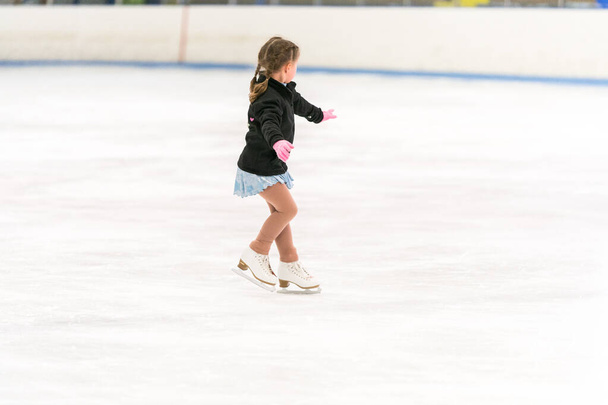 Menina praticando patinação artística em uma pista de patinação no gelo interior. - Foto, Imagem