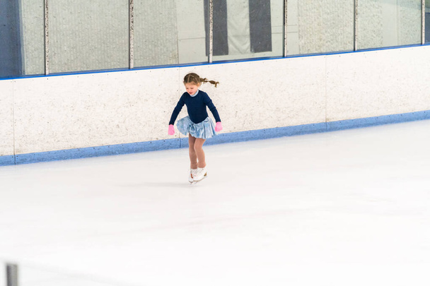 Little girl practicing figure skating on an indoor ice skating rink. - Fotó, kép