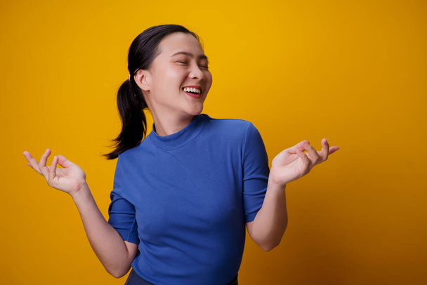 Happy Asian woman showing toothy smile standing isolated over yellow background. - Photo, Image