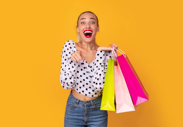 Überglückliche Frau mit Einkaufstüten, die auf dich zeigen - Foto, Bild
