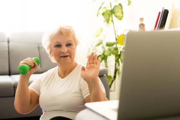Entraînement domestique. Femme âgée active faisant Exersise devant l'ordinateur portable à la maison, Espace libre - Photo, image