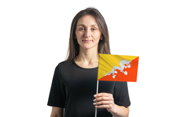 Ευτυχισμένο νεαρό λευκό κορίτσι που κρατά τη σημαία του Μπουτάν απομονωμένη σε λευκό φόντο. - Φωτογραφία, εικόνα