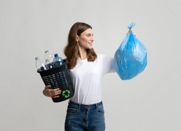 Smistamento rifiuti. Positivo Lady Holding Bag con immondizia e bottiglie di plastica secchio - Foto, immagini
