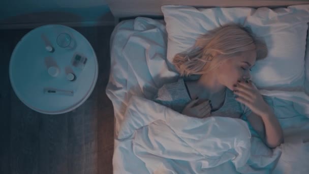 vista superior de la mujer enferma tosiendo mientras está acostada en la cama por la noche - Metraje, vídeo