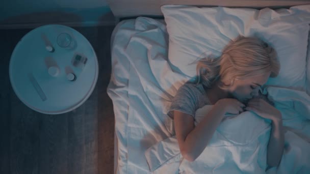 vista superior de la mujer enferma mirando el termómetro digital mientras está acostada en la cama - Metraje, vídeo
