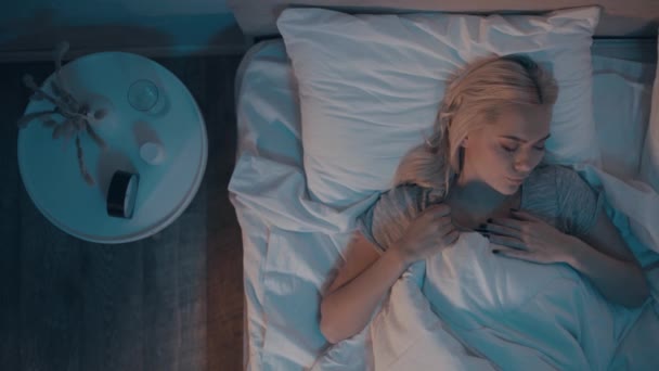 vista superior de la mujer con trastorno del sueño mirando el despertador por la noche - Metraje, vídeo
