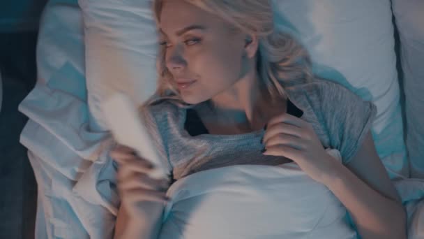 κορυφαία άποψη της γυναίκας βάζοντας μακριά smartphone, σβήνοντας το φως και πρόκειται να κοιμηθεί - Πλάνα, βίντεο