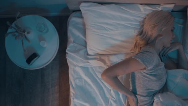 ylhäältä näkymä nainen kärsii selkäkipu kun makaa sängyssä yöllä - Materiaali, video