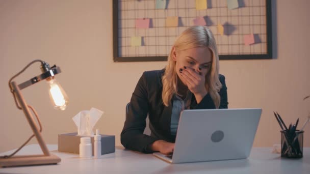 sick businesswoman sneezing in napkin while using laptop in office - Filmagem, Vídeo