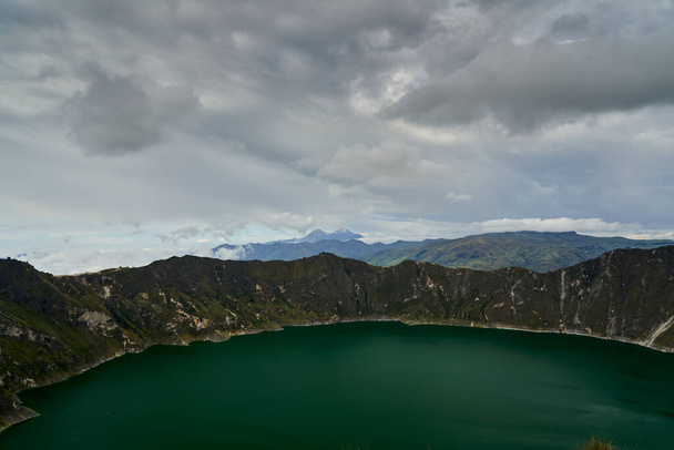 Beautiful quilotoa crater lake in Ecuador, South America with turquoise water inside a volcanic caldera with snow capped andes mountains in the background is famous for hikers and back packers - Φωτογραφία, εικόνα