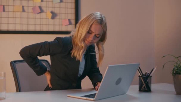 mujer de negocios rubia que sufre de dolor de espalda en la oficina  - Imágenes, Vídeo