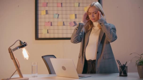ciężarna bizneswoman cierpiąca na migrenę w biurze  - Materiał filmowy, wideo