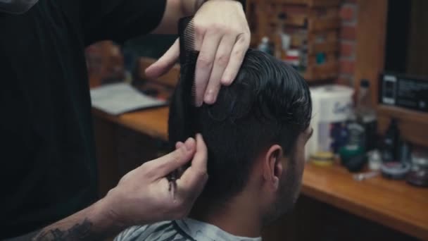 Barbiere che taglia capelli di cliente in negozio di barbiere  - Filmati, video