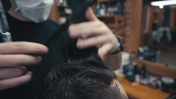 Περικοπή άποψη του κομμωτή κοπής μαλλιά του πελάτη στο κουρείο  - Πλάνα, βίντεο
