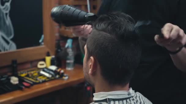 Парикмахер сушит волосы человека в парикмахерской  - Кадры, видео