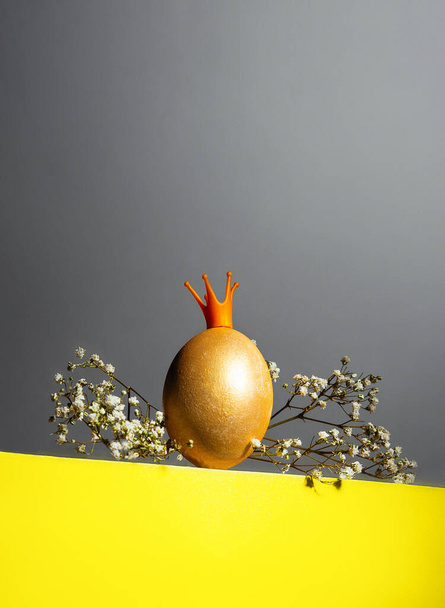 Golden egg in crown on yellow and gray background, easter concept while covid-19 isolated - Фото, изображение