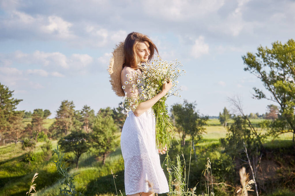 a girl in a white dress with a bouquet of flowers is walking in the field - Foto, immagini