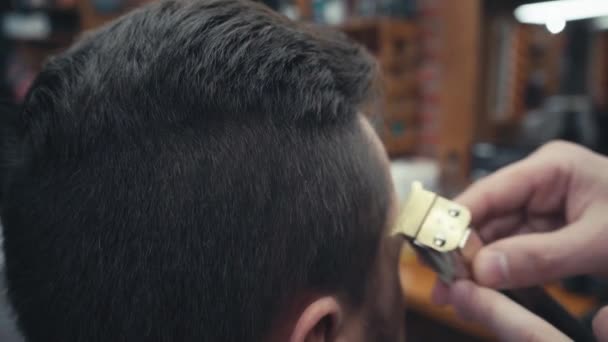 Vista de perto do barbeiro aparando o cabelo do homem na barbearia - Filmagem, Vídeo