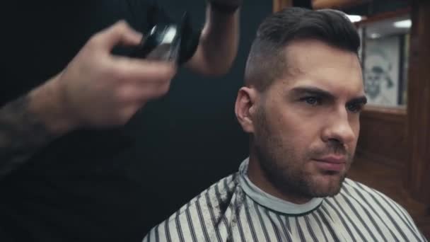 Татуированный парикмахер стрижет и расчесывает волосы клиента - Кадры, видео