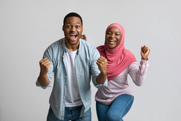 Emozionale coppia nera che celebra il successo, stringendo pugni e urlando - Foto, immagini