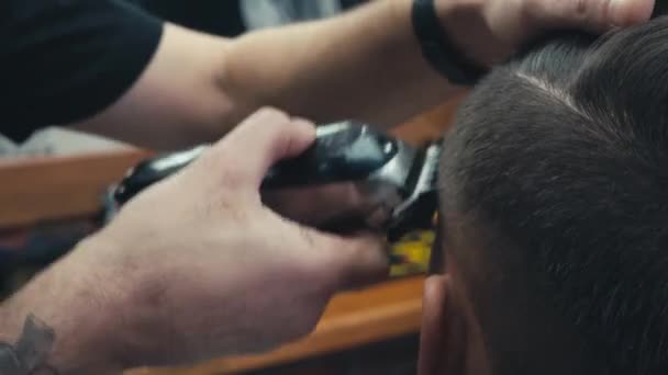 Vista de cerca del peluquero utilizando trimmer mientras trabaja con el cliente  - Metraje, vídeo