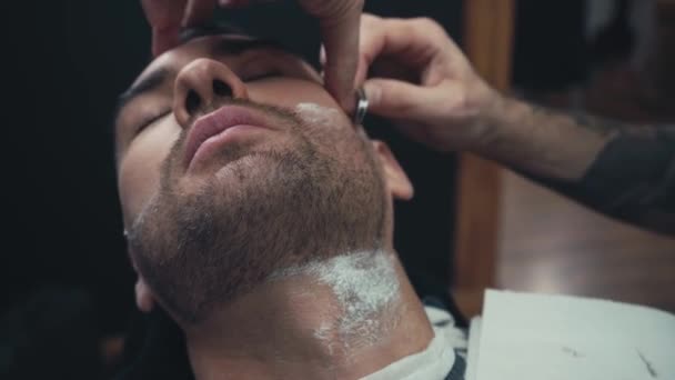 Barber styling beard of client with razor  - Footage, Video