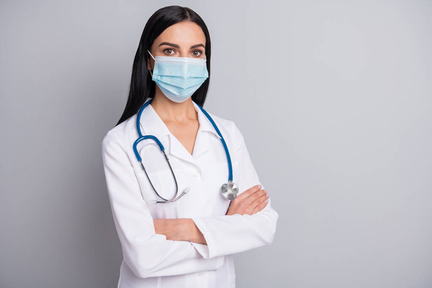Photo of confident serious lady doctor wear white coat face mask arms crossed empty space isolated grey color background - Zdjęcie, obraz