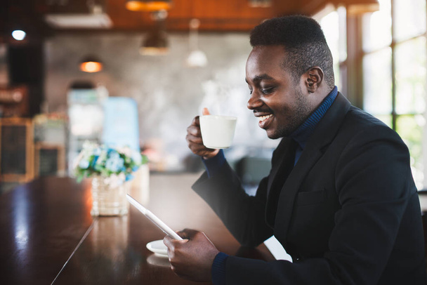 African businessman using tablet computer in coffee shop - Fotó, kép