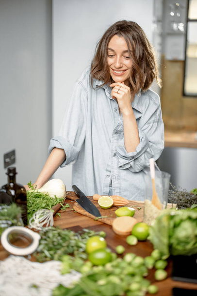 Mutfakta yeşil malzemeleri olan bir kadın. - Fotoğraf, Görsel