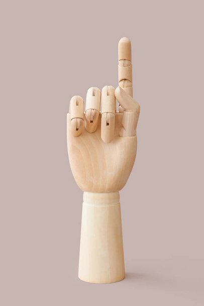 Wooden hand with raised index finger on color background - Photo, Image