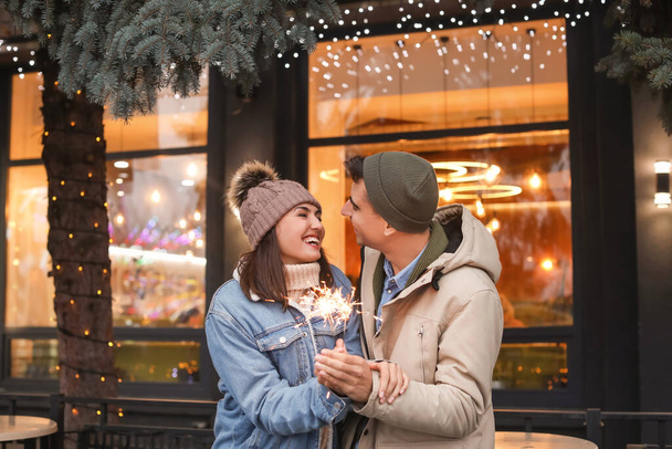 Happy young couple with Christmas sparklers outdoors on winter day - Φωτογραφία, εικόνα
