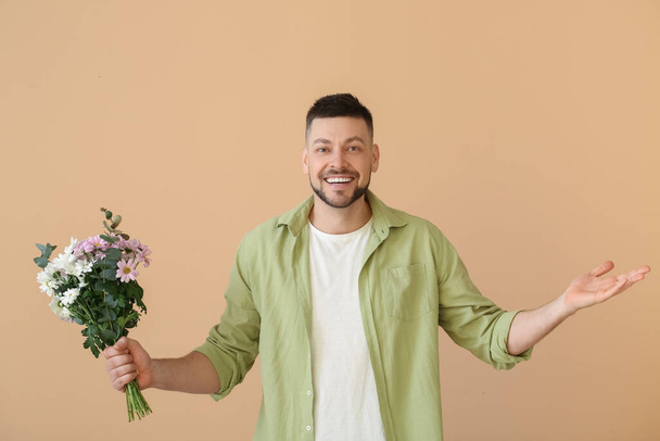Hezký muž s kyticí krásných květin na barevném pozadí - Fotografie, Obrázek