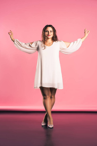 Plus size fashion model in beige dress, fat woman on pink background, body positive concept - Фото, изображение