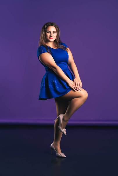 Happy plus size model in blue dress on purple background, body positive concept - Photo, Image
