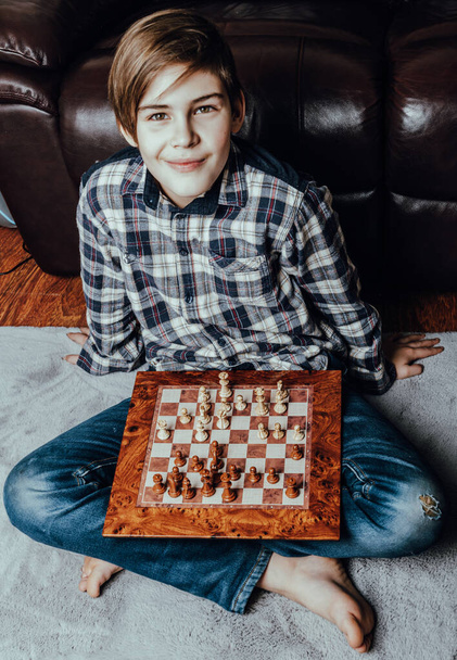 Caucasian teenager boy playing chess in grey carpet, education, activity and hobby at home concept - Foto, immagini