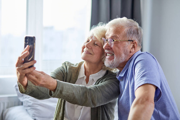 beautiful happy elderly couple taking photo on smartphone - Photo, Image