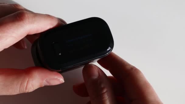 Női kéz tartja digitális impulzus oximéter és nézi eszköz - Felvétel, videó