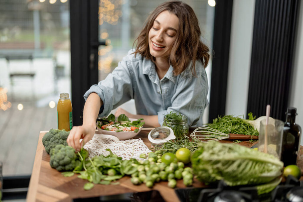Woman cooking healthy green salad in kitchen - Foto, Imagen