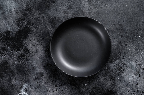 Black plate on textured black background. Top view. Copy space - Foto, immagini