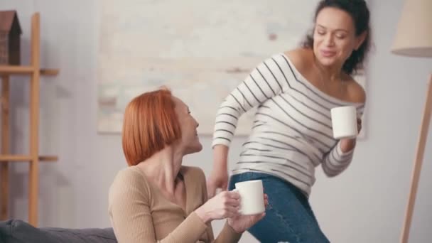 Femme hispanique donnant tasse à petite amie heureuse avec smartphone - Séquence, vidéo