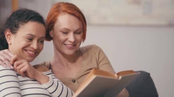 Ευτυχισμένη Ισπανίδα γυναίκα διαβάζει βιβλίο δυνατά κοντά στην κοκκινομάλλα φίλη της. - Πλάνα, βίντεο