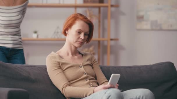 hispanische Frau schenkt rothaarige Freundin mit Smartphone Valentinen - Filmmaterial, Video