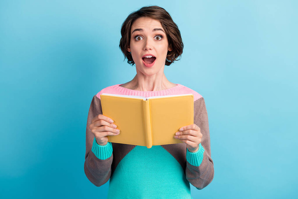 Photo portrait of amazed surprised schoolgirl staring with opened mouth keeping yellow book isolated on vibrant color blue background - Valokuva, kuva
